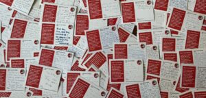 A pile of hundreds of red and white postcards with the message "fight the anti refugee laws" on them