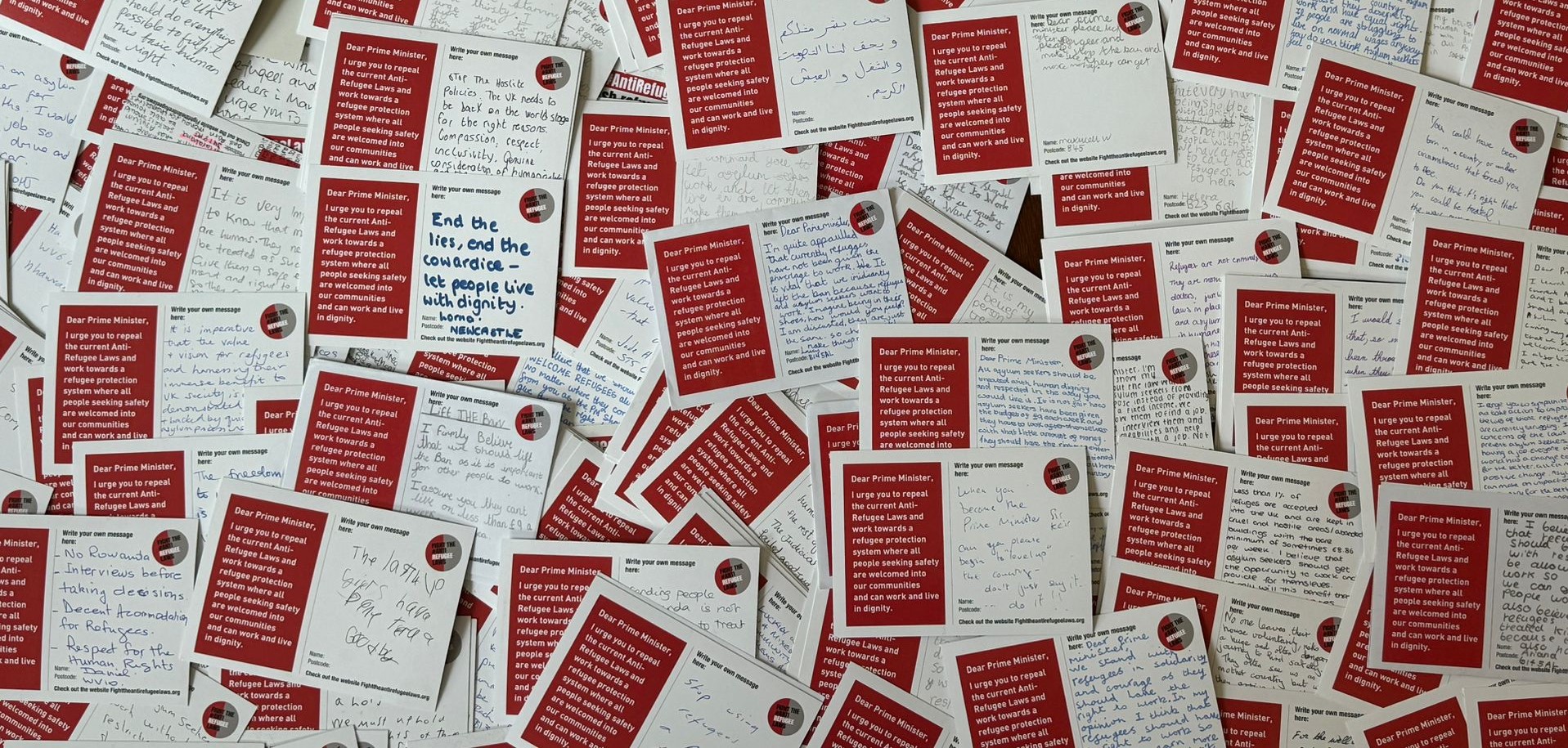 A pile of hundreds of red and white postcards with the message "fight the anti refugee laws" on them