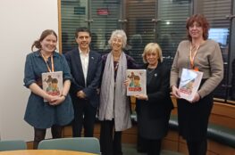 A line of people holding a colourful report document