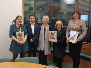 A line of people holding a colourful report document